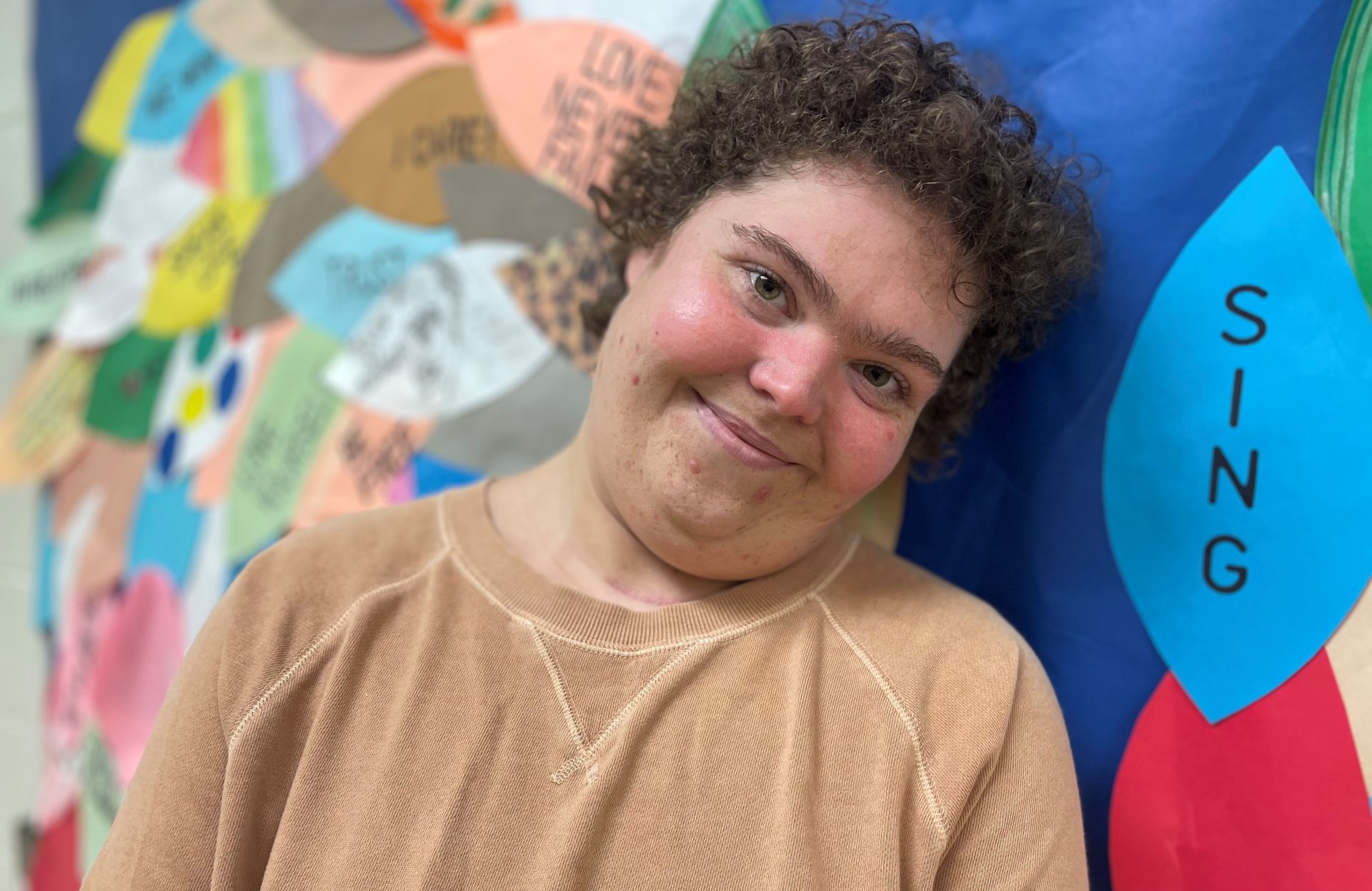 Smiling woman leaning against colorful bulletin board
