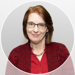 Smiling woman with glasses and red shirt and sweater