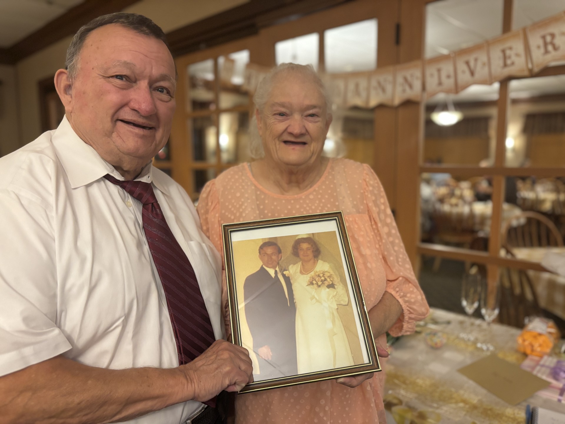 Elderly man and woman holding photo of their wedding day 50 years ago