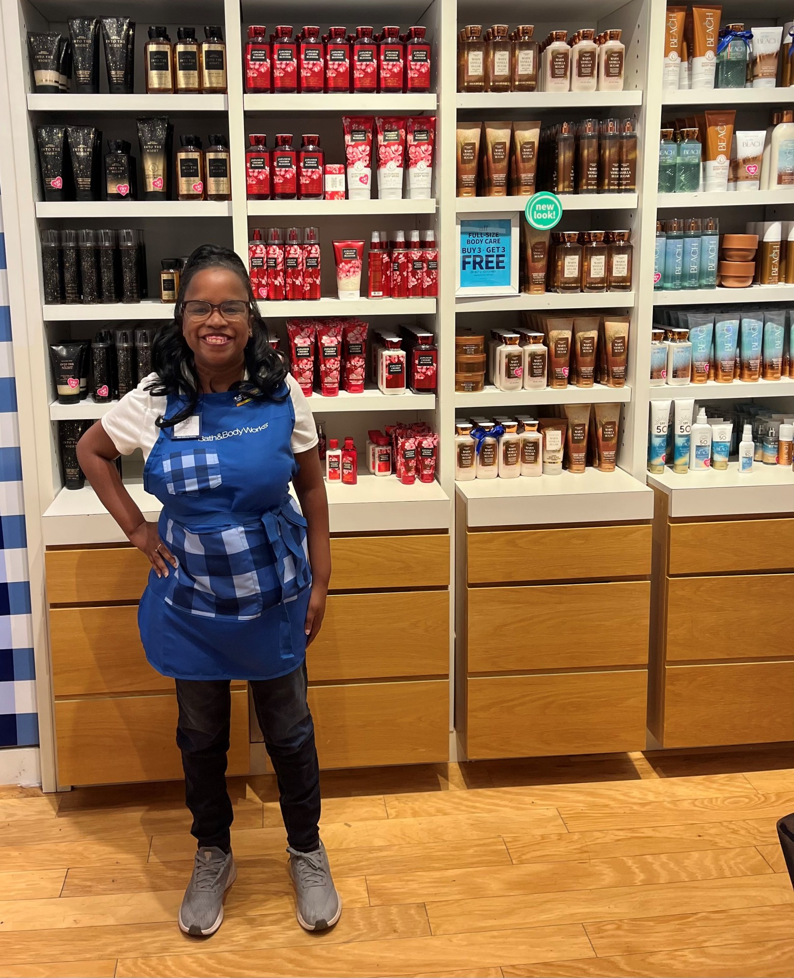Smiling woman standing in front of colorful store shelves stocked with lotions